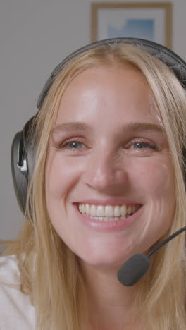 Vertical-Video-Close-Up-Of-Woman-With-Controller-Wearing-Headset-Sitting-On-Sofa-At-Home-Gaming-Online-1